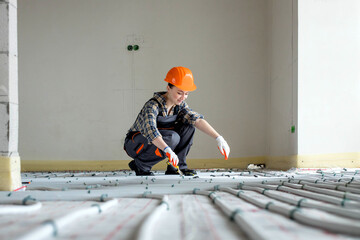 Woman worker is installing underfloor heating system. Warm floor heating system