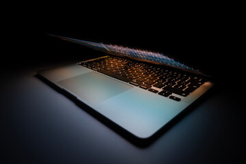 Half-open modern aluminium ultrabook with backlight keyboard on the table at night