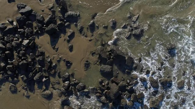 Aerial top-down slow clockwise spin view of boulders and surf Video 9