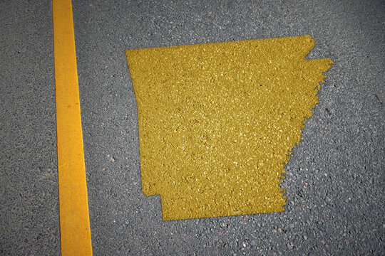 yellow map of arkansas state on asphalt road near yellow line.