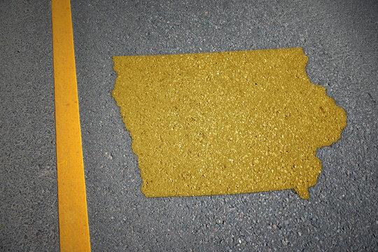 yellow map of iowa state on asphalt road near yellow line.