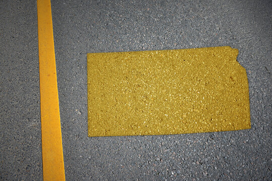 yellow map of kansas state on asphalt road near yellow line.
