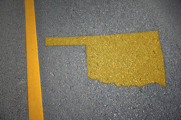 yellow map of oklahoma state on asphalt road near yellow line.