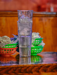Water glasses and food boats are bused to this table while the waitstaff is too busy to return to the kitchen.  A Busy restaurant with tables that have not been cleared yet.