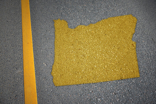 yellow map of oregon state on asphalt road near yellow line.