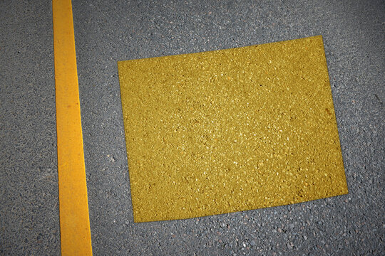 yellow map of wyoming state on asphalt road near yellow line.