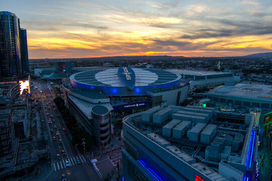 aerial shot of Crypto.com Arena and the Los Angeles Convention Center at sunset with cars driving on the street, skyscrapers, hotels and office buildings in the skyline in Los Angeles California USA