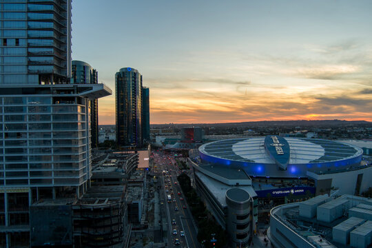 aerial shot of Crypto.com Arena and the Los Angeles Convention Center at sunset with cars driving on the street, skyscrapers, hotels and office buildings in the skyline in Los Angeles California USA