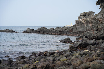 a beach with basalt.
calm waves and blue sky