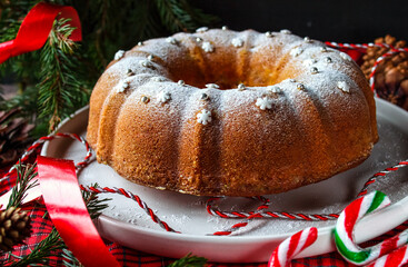Christmas cake decorated with powdered sugar, snowflakes and silver balls. Homemade Christmas or New Year's cake on a white plate.