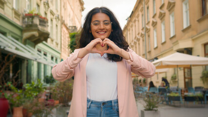 Smiling happy young teen Indian Arabian woman female lady girl making heart shape hands to camera...