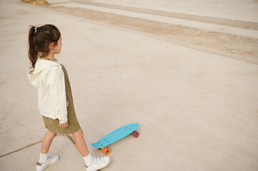 Little child girl skateboarding on urban skatepark. Top view. Happy active childhood. Extreme sport. Leisure activity