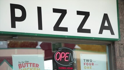 pizza word caption text writing sign above window with animated flashing changing neon open sign in summer exterior outside store storefront pizzeria