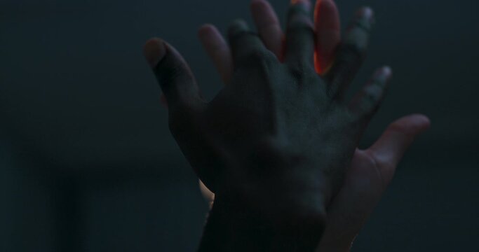 Dark skinned man's hand and white shinned female's woman's hands touchig each other dancing in front of against bright light in the studio repeating different poses. Multinational concept.