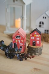 Colorful miniature wooden houses arranged in a row against a beautiful background. Small pink souvenir houses. DIY wooden products. Decor for New Year and Christmas. Christmas tree toys.