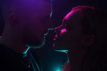 Silhouettes of a couple nearly kissing, surrounded by neon lights and intimate shadows