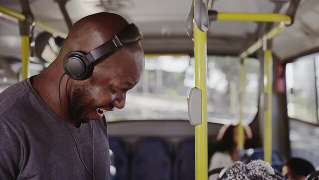 Homem sorridente com fones de ouvido em pe no onibus. Cinematico 4k.