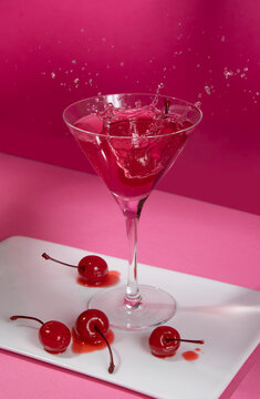 Pink cocktail with splash and cherries
