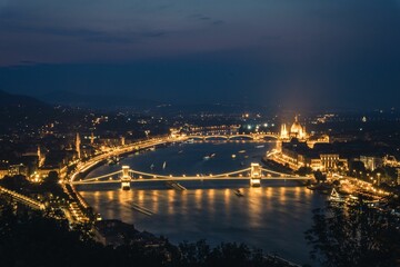 Fototapeta na wymiar a long bridge across the water next to a mountain near the city: Hungary, Budapest