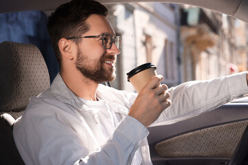 Coffee to go. Happy man with paper cup of drink in car