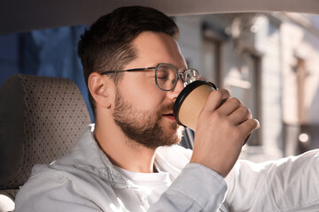 To-go drink. Handsome man drinking coffee in car