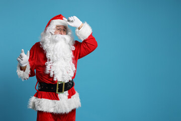 Fototapeta na wymiar Merry Christmas. Santa Claus posing on light blue background, space for text