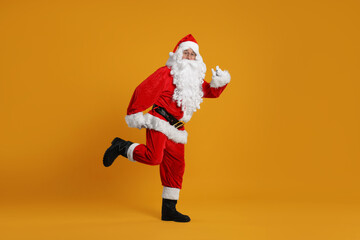Fototapeta na wymiar Merry Christmas. Santa Claus posing on orange background