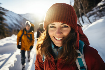 Fototapeta na wymiar Joyful woman in a red beanie leading a group of hikers in a sunlit snowy mountain trail.