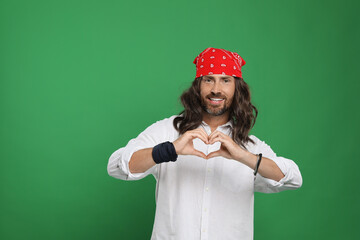Hippie man making heart with hands on green background