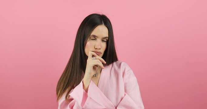 Puzzled brunette hair woman wear pink dress thinking about something and scratching her head, touch chin while standing isolated on pink studio background. Thinking uncertain woman, not sure.