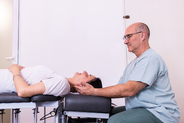 Male chiropractor massaging the neck of a woman in casual clothes at private clinic