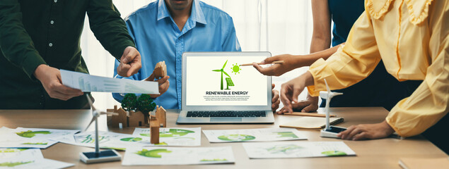 Renewable energy logo displayed on green business laptop while business team represented green...