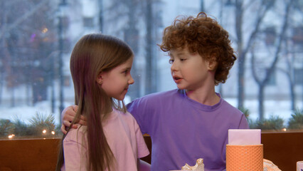Children sitting together at a table in a restaurant. Stock footage. Brother with red curly hair...