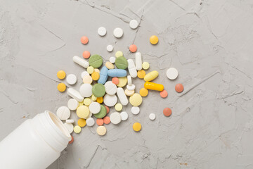 Jar with different medical pills and capsules on concrete background, top view