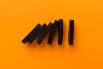 Black domino tiles on color background, top view