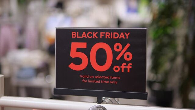 Close-up of Black Friday signboard in clothing store. Cinematic shot of limited sale collection on Black Friday at evening clothing store. Concept of buying sale limited collection on Black Friday