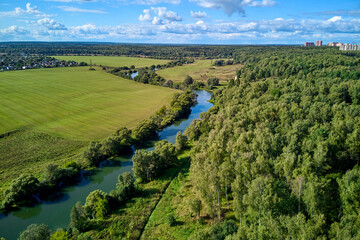 Aerial view of the river bed winding between fields and forest