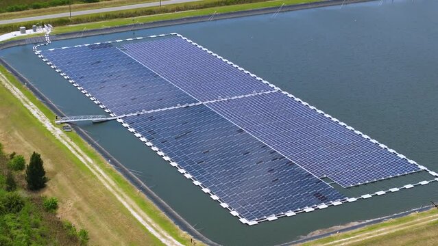 Industrial pond with floating photovoltaic solar panels for producing clean electrical energy. Concept of renewable electricity on water surface with no air pollution