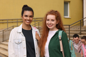Portrait of happy young students with backpacks outdoors