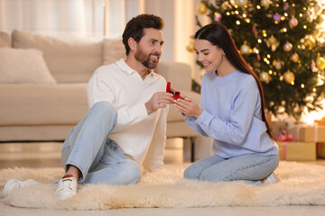 Man with engagement ring making proposal to his girlfriend at home on Christmas