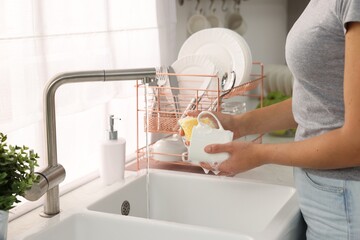 Woman washing cup at sink in kitchen, closeup