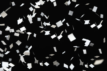 White confetti falling down on black background