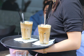Close up of a Waitress bringing two Ice coffees to a customer