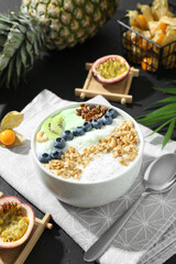 Tasty smoothie bowl with fresh kiwi fruit, blueberries and oatmeal served on black table
