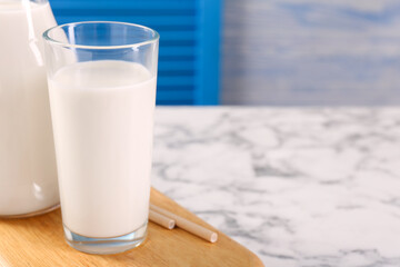 Glassware with tasty milk on white marble table, closeup. Space for text