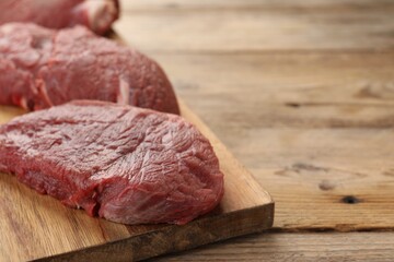 Pieces of raw beef meat on wooden table, space for text