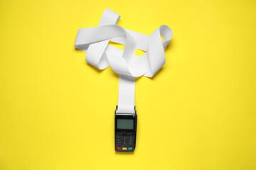 Payment terminal with thermal paper for receipt on yellow background, top view