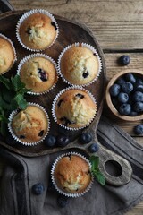 Delicious sweet muffins with blueberries and mint on wooden table, flat lay