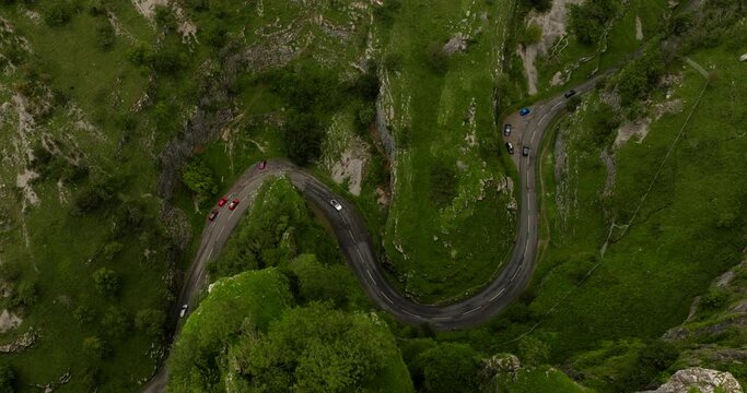 Epic aerial view of cars driving the serpentine Cheddar Gorge road in evergreen nature landscape in Britain