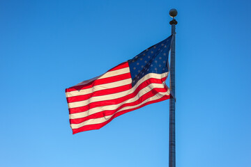 waving USA flag on pole against blue sky